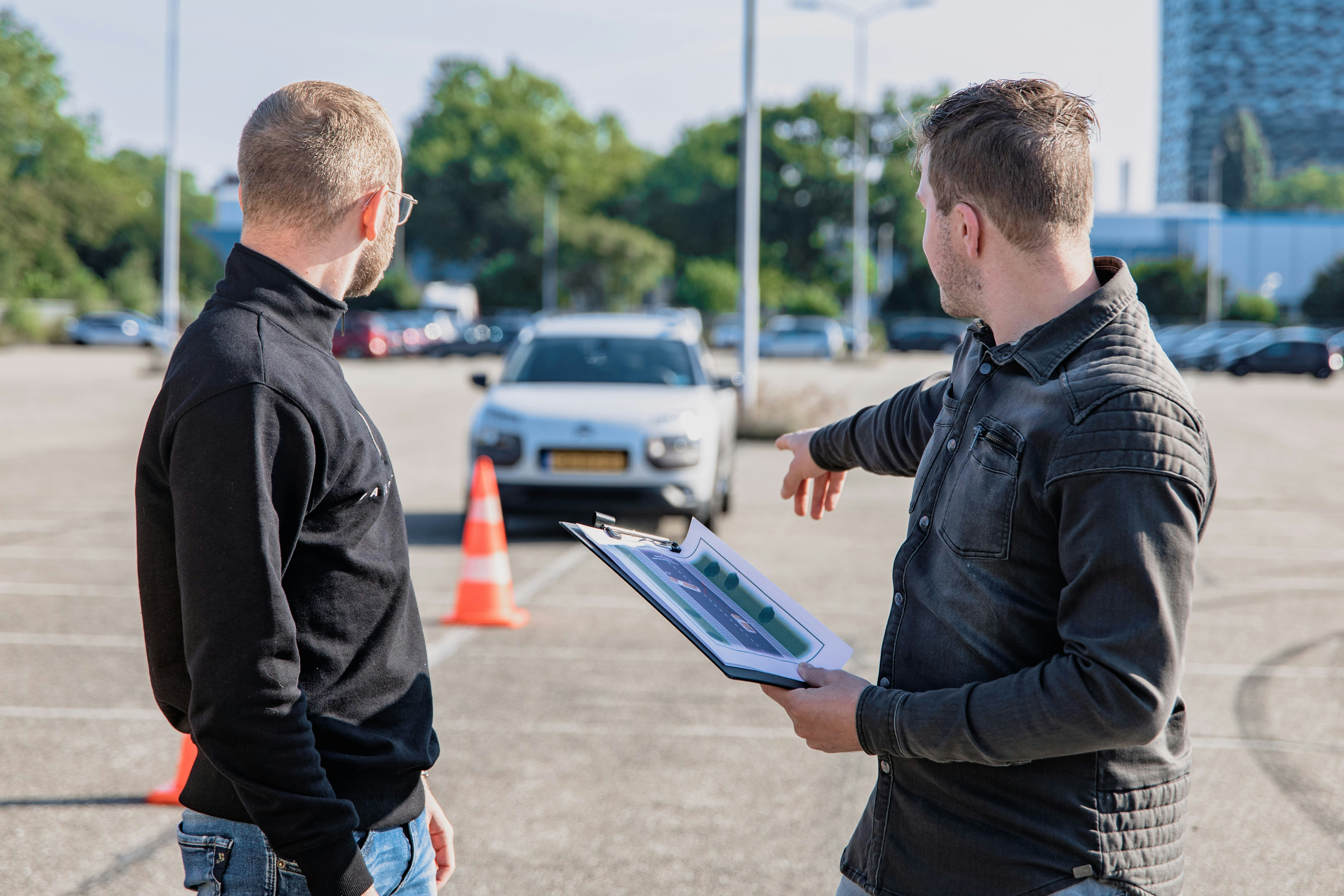Moniteur accueillant un nouvel élève à côté d'une voiture-école.