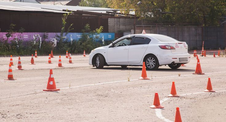 Voiture-école effectuant un parcours avec cônes — préparation à l'examen pratique SAAQ.